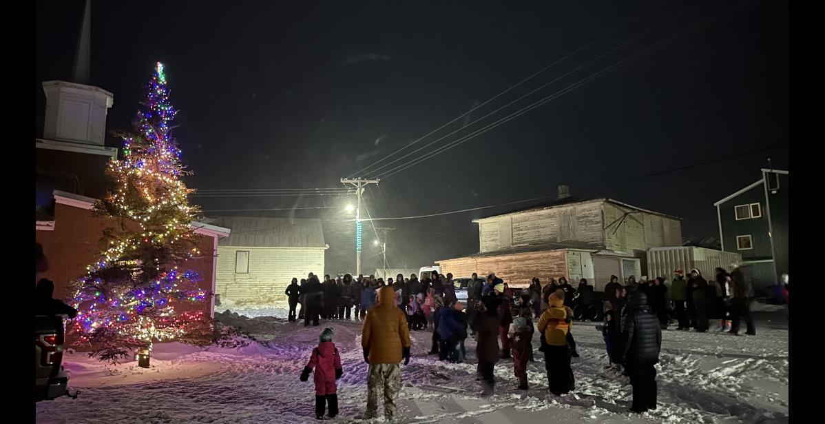 Photo by Kelsi Ivanoff UNALAKLEET HOLIDAY TREE LIGHTING— Community members in Unalakleet gathered to sing outside the Covenant Church after the community tree was lit.