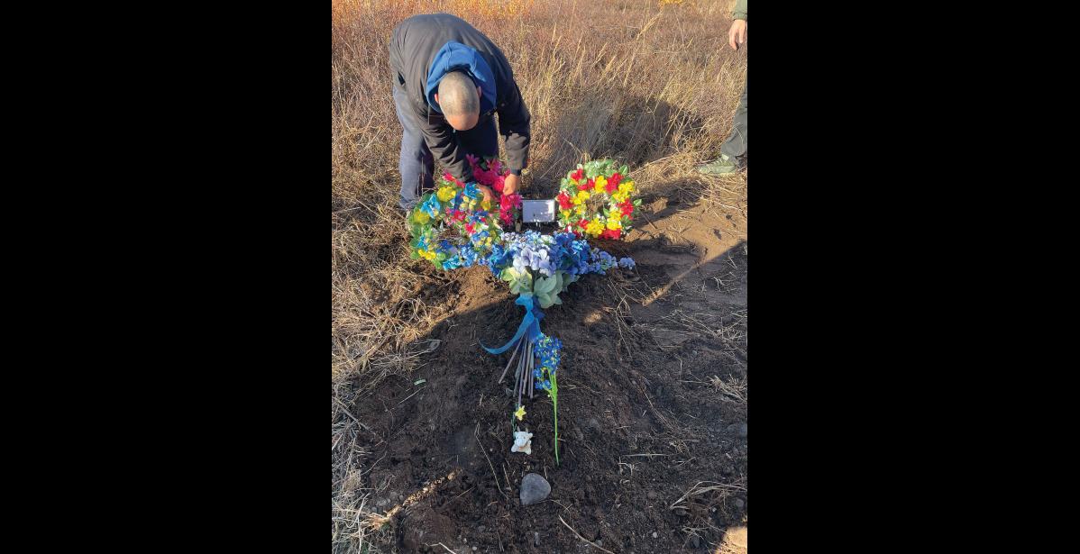 FLOWERS – Leonard Anawrok places flowers on Edward Angalook’s grave in Unalakleet. Photo courtesy of Amber Cunningham