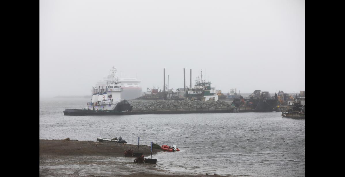 Photo by Diana Haecker The port is busy with gravel operations on the causeway and several visits from cruise ships. Pictured is a barge loaded with rock, with the cruiseship Roald Amundsen docked in the background, on Friday, August 18.